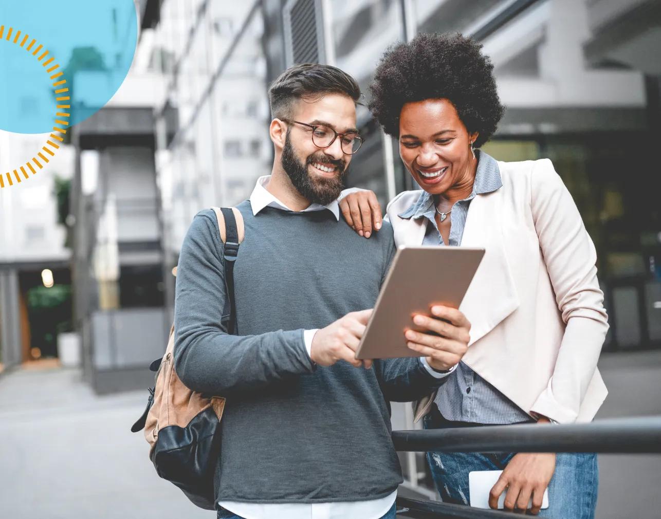 man and woman collaborating on a project on a tablet while working outside the office